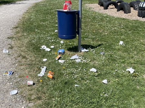Müll, verteilt um den Abfallbehälter auf dem Spielplatz am Rehmenbach